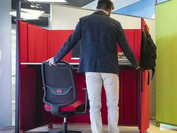 Un uomo si siede nella sua postazione ufficio fatto di pannelli insonorizzanti e alti