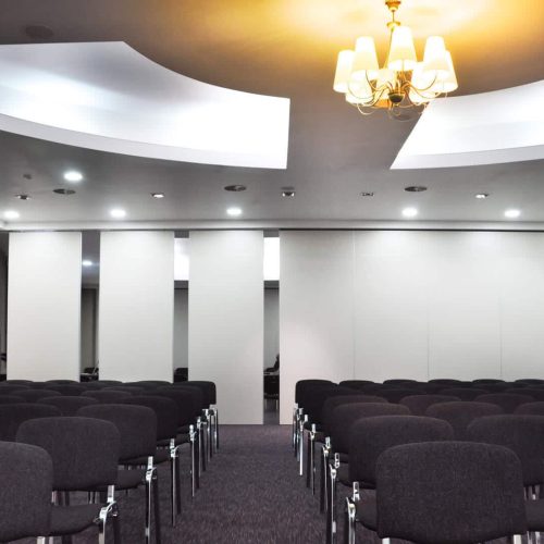 Sala conferenze arredata con sedie nere e pareti grigie